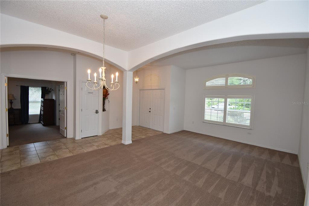 A living room features carpeted flooring, a chandelier, arched architectural details, and a tiled entryway — 192 PINE GROVE DRIVE, PALM COAST, FL