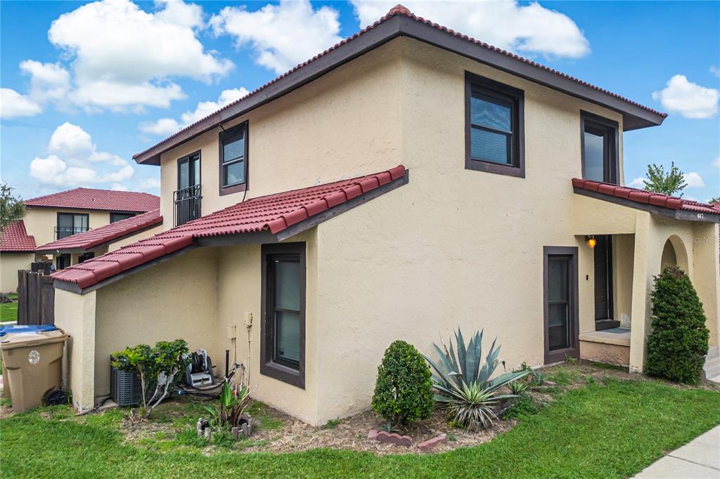 A two-story stucco townhouse with a red tile roof and dark-framed windows — 447 HUNTER CIRCLE, KISSIMMEE, FL