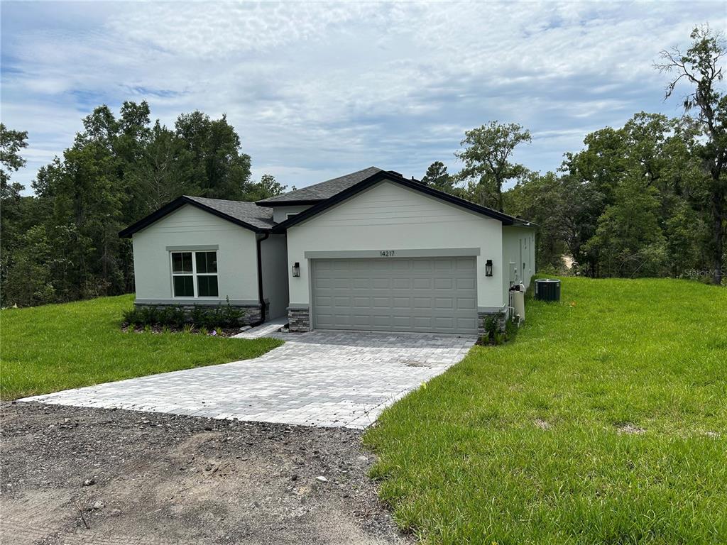 A single-story house with a light-colored exterior, a two-car garage, and a paved driveway — 14217 EARLINE ROAD, BROOKSVILLE, FL