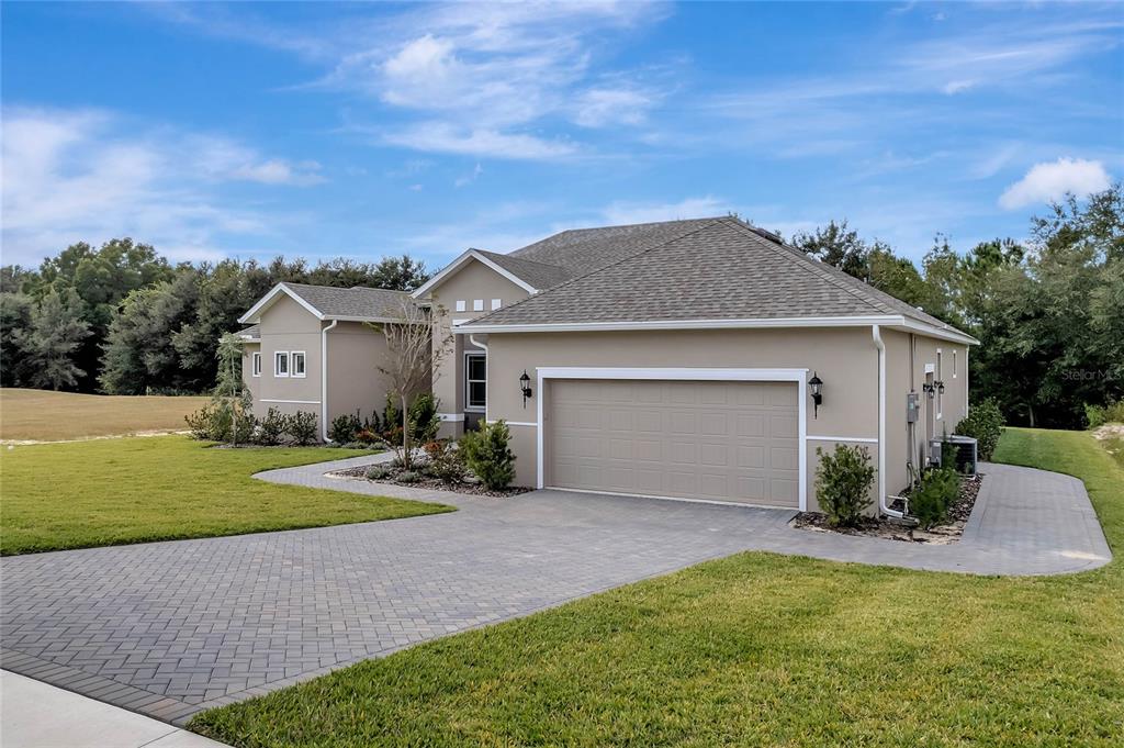 A beige single-story house with a two-car garage and a paved driveway — 4049 PINNACLE PLACE, LADY LAKE, FL