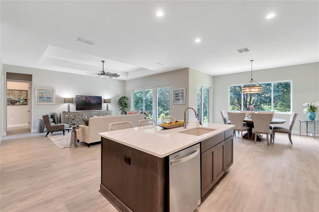 An open-concept kitchen and living area featuring a large island, light flooring, and recessed lighting — 4049 PINNACLE PLACE, LADY LAKE, FL