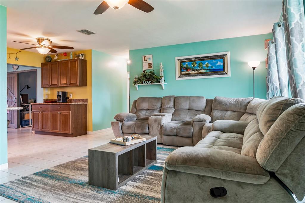 A living room features a gray sectional sofa, a coffee table, and turquoise walls — 140 BARRE DRIVE NW, PORT CHARLOTTE, FL