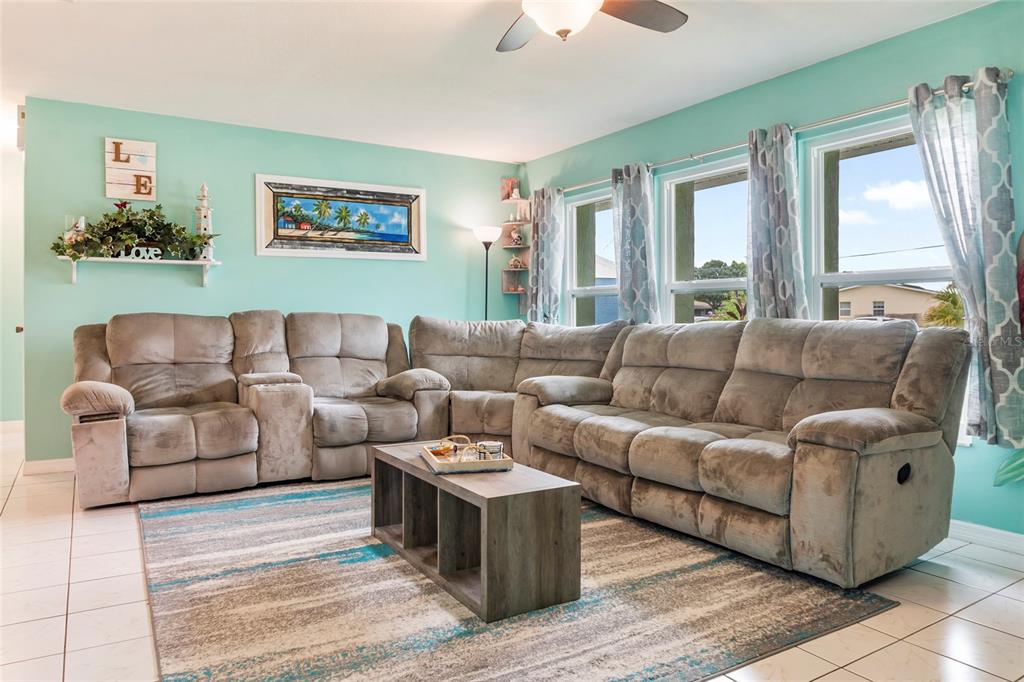 A living room features a large gray sectional sofa, a coffee table, and teal walls — 140 BARRE DRIVE NW, PORT CHARLOTTE, FL