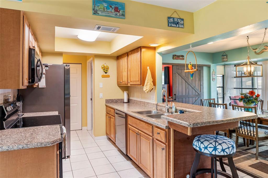 A kitchen with wood cabinets, laminate countertops, a breakfast bar, and tile flooring — 140 BARRE DRIVE NW, PORT CHARLOTTE, FL