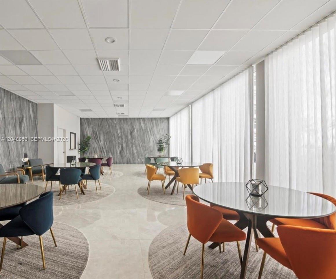 A modern lounge area features glass tables, colorful chairs, and marble-patterned accent walls — 3140 S Ocean Dr # 1003, Hallandale Beach FL 33009, HALLANDALE BEACH, FL
