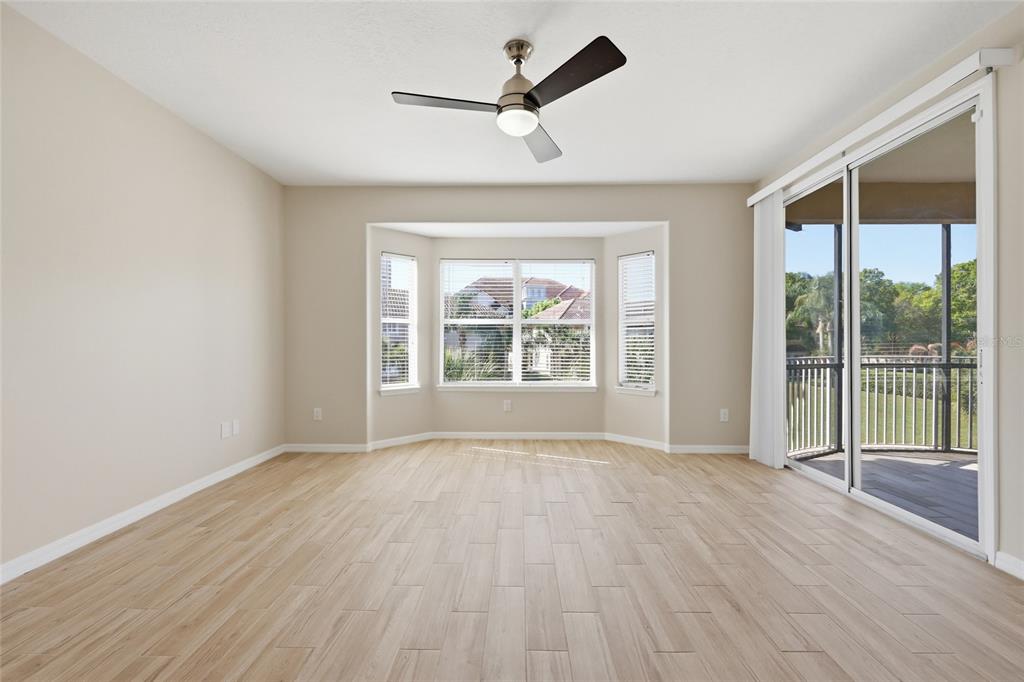 An empty room features light wood-look tile flooring, a ceiling fan, and a bay window — 8718 THE ESPLANADE UNIT 14, ORLANDO, FL