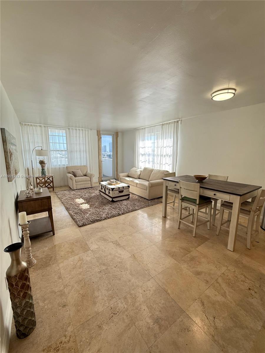 A living and dining room features beige tile floors, neutral furniture, and large windows — 100 Lincoln Rd # 1111, Miami Beach FL 33139, MIAMI BEACH, FL