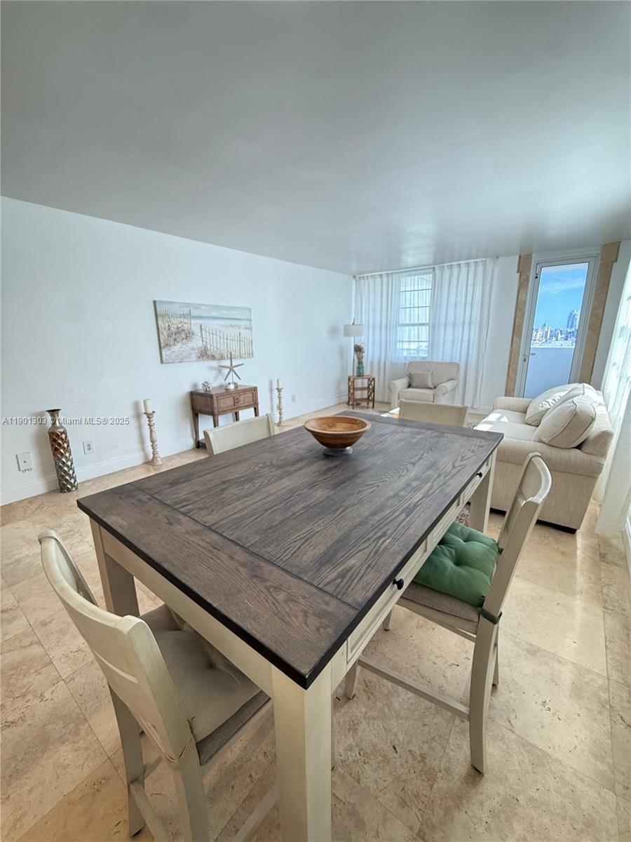 A dining area with a wooden table and chairs opens into a bright living space — 100 Lincoln Rd # 1111, Miami Beach FL 33139, MIAMI BEACH, FL