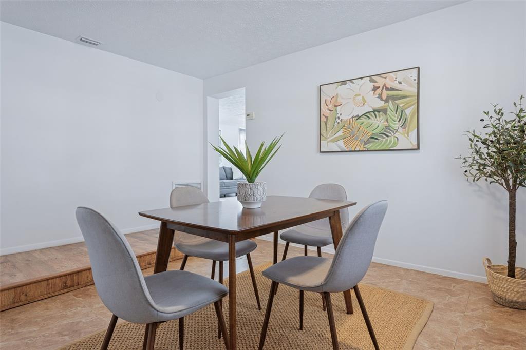 A living room features a white sofa, two gray chairs, a coffee table, and artwork — 8105 ALPINE AVENUE, TAMPA, FL