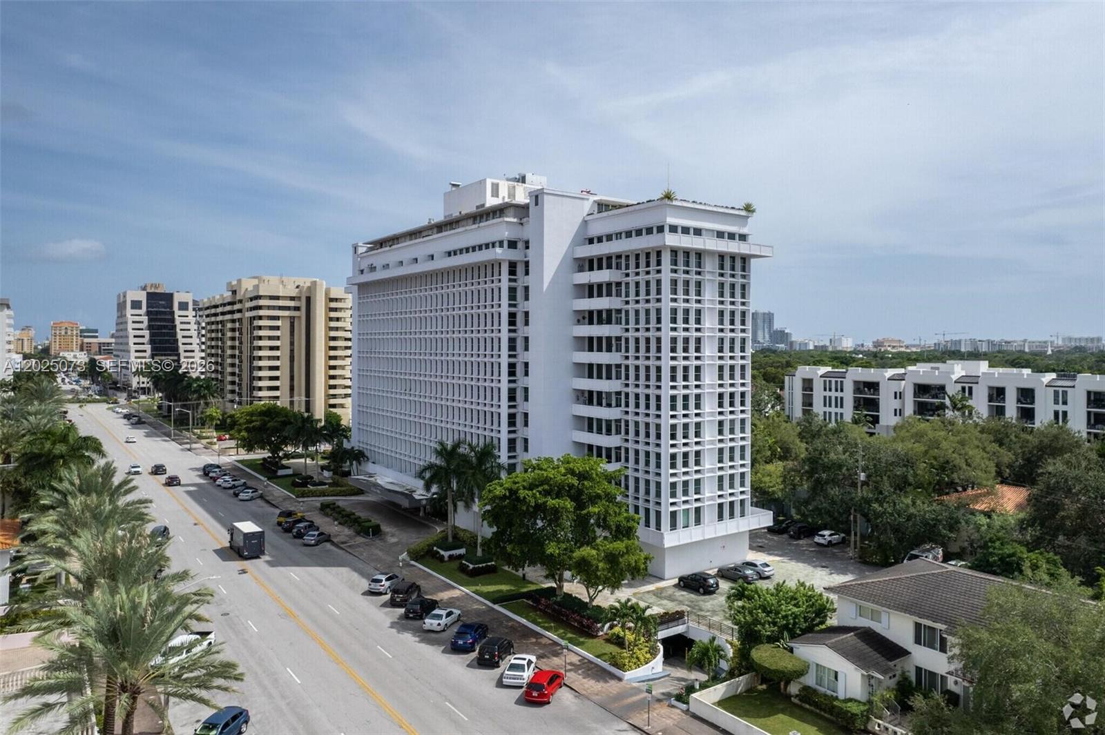 An aerial view shows a tall white apartment building situated next to a busy road — 700 Biltmore Way # 719, Coral Gables FL 33134, CORAL GABLES, FL