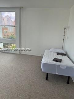 A bedroom with beige carpet, a single bed, and a large window overlooking city buildings — 700 Biltmore Way # 719, Coral Gables FL 33134, CORAL GABLES, FL