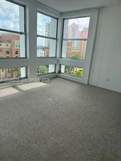 An empty room with beige carpet and large windows overlooking a city skyline — 700 Biltmore Way # 719, Coral Gables FL 33134, CORAL GABLES, FL