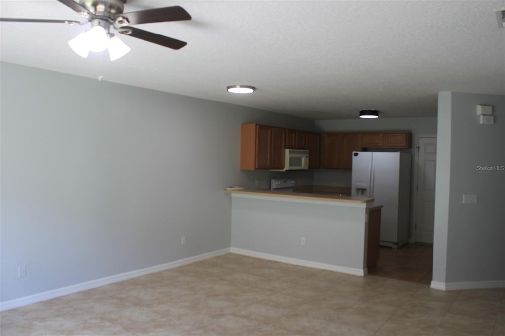 An open-concept kitchen with wood cabinets and a breakfast bar overlooks a tiled living area — 669 CRESTING OAK CIRCLE UNIT 30, ORLANDO, FL