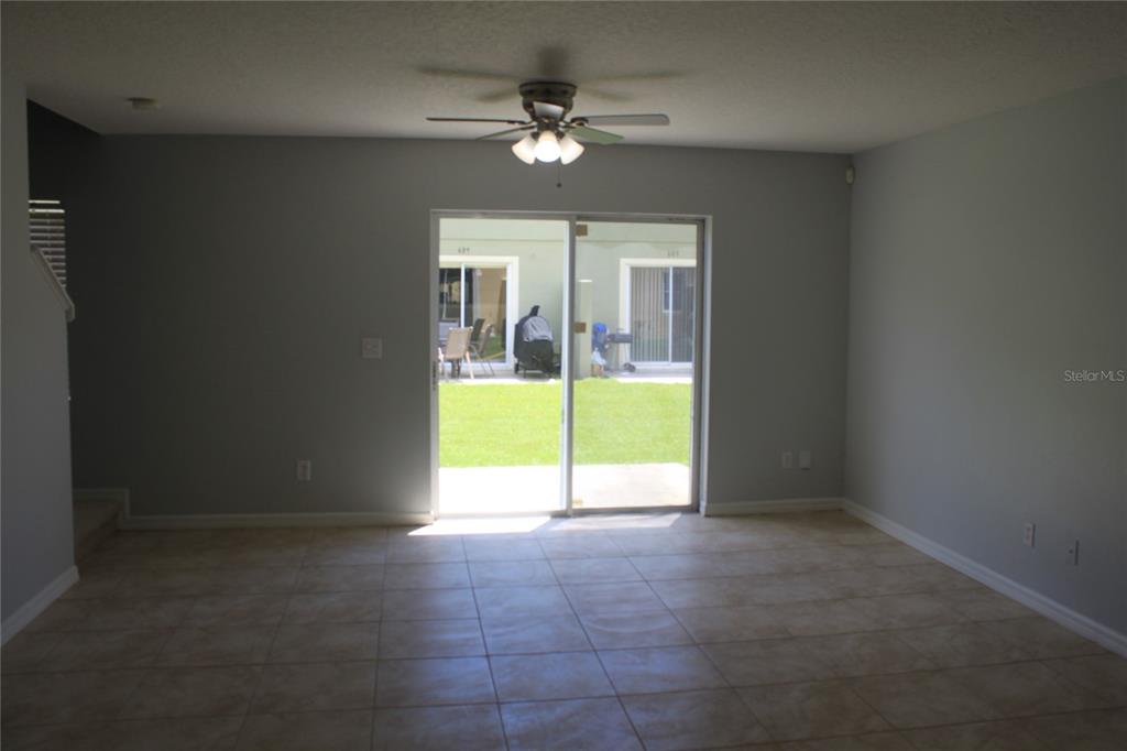 An empty room with light-colored tile flooring, a ceiling fan, and sliding glass patio doors — 669 CRESTING OAK CIRCLE UNIT 30, ORLANDO, FL