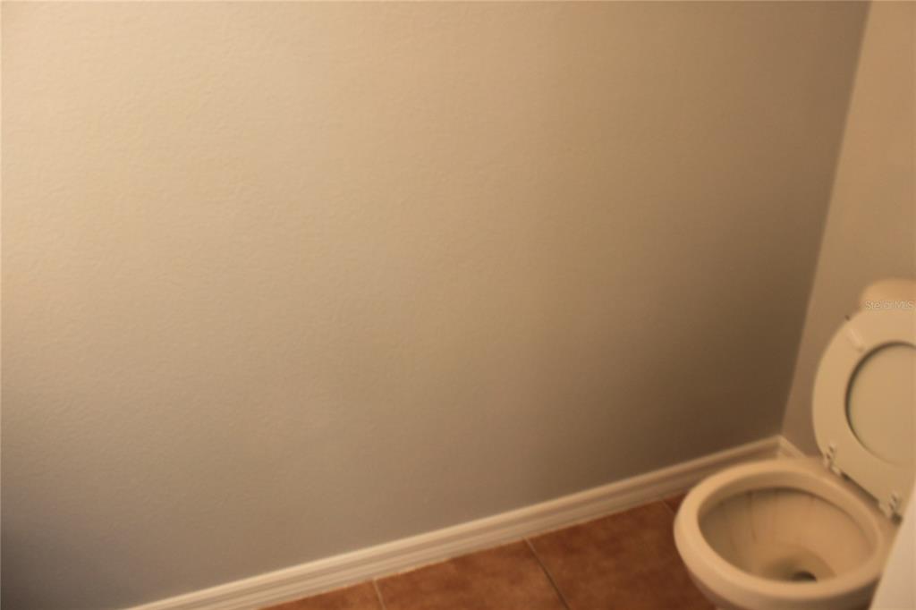 A partial view of a bathroom with a toilet and light-colored walls — 669 CRESTING OAK CIRCLE UNIT 30, ORLANDO, FL