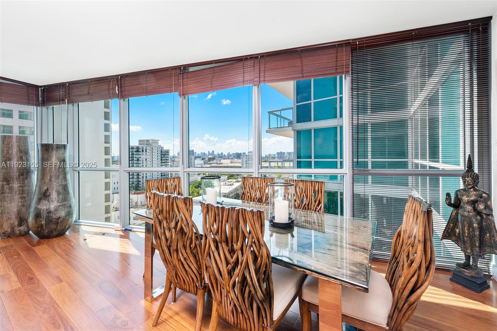 A dining room features a glass-topped table, woven chairs, and floor-to-ceiling windows overlooking a city — 101 20th St # 1706, Miami Beach FL 33139, MIAMI BEACH, FL