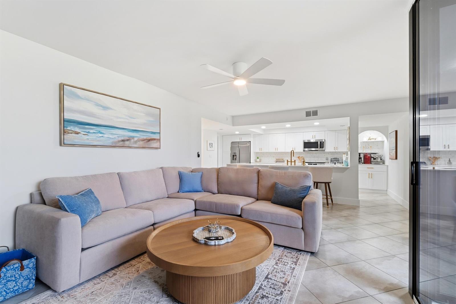 A living room with a sectional sofa, round coffee table, and an open kitchen beyond — 2455 Lindell Boulevard # 3103, Delray Beach FL 33444, DELRAY BEACH, FL