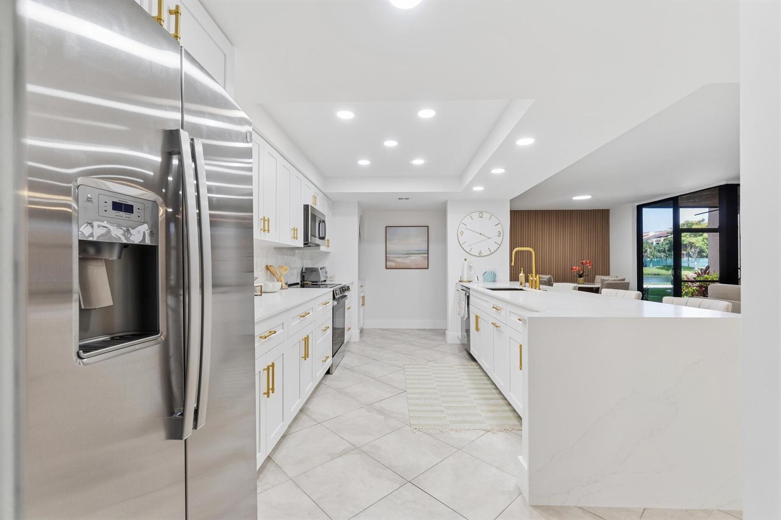 A modern white kitchen features gold hardware, stainless steel appliances, and a large quartz island — 2455 Lindell Boulevard # 3103, Delray Beach FL 33444, DELRAY BEACH, FL