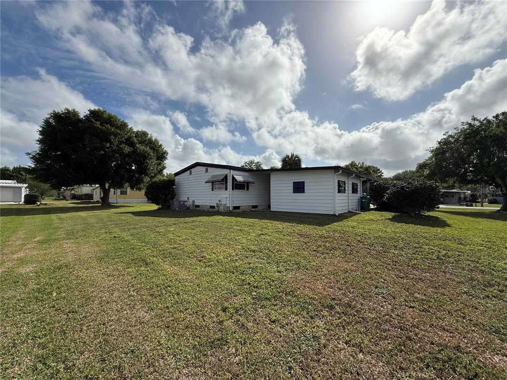 A side view of a white mobile home with a large grassy yard — 11 N BOBWHITE ROAD, WILDWOOD, FL