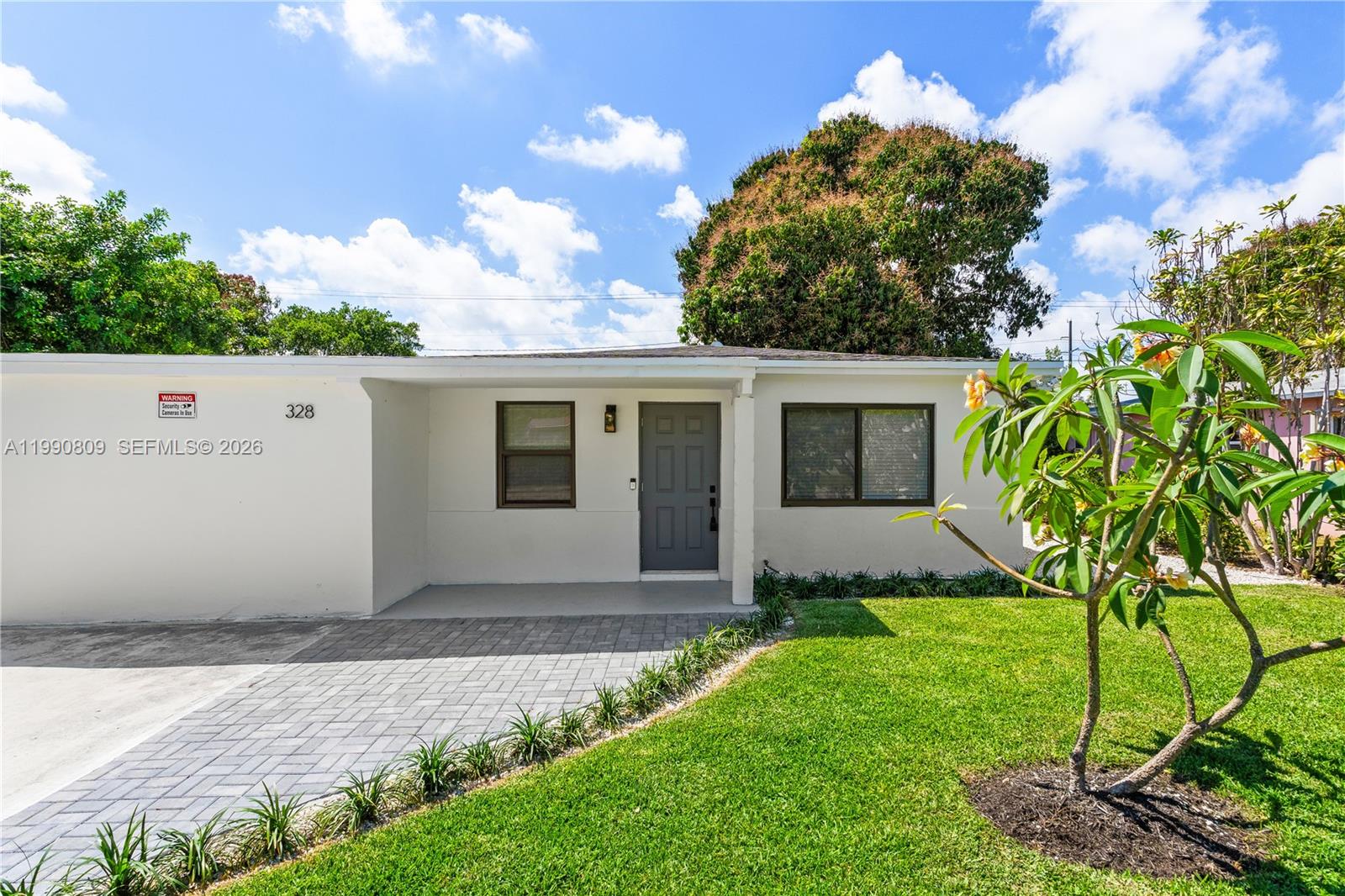 A single-story house with a gray front door, paved driveway, and a small front lawn — 328 SW 11th Ave, Delray Beach FL 33444, DELRAY BEACH, FL