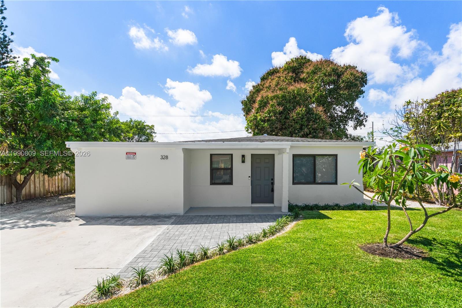 A single-story house with a paved driveway, a small front porch, and a green lawn — 328 SW 11th Ave, Delray Beach FL 33444, DELRAY BEACH, FL
