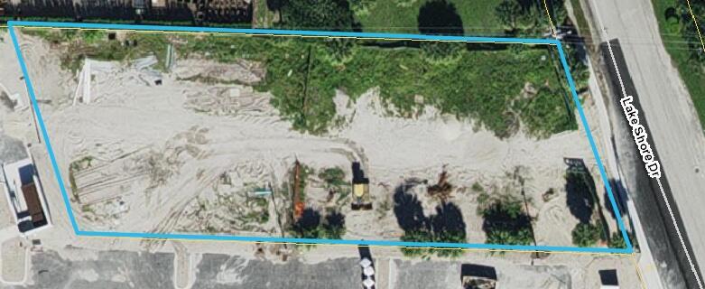 This aerial view shows a vacant, sandy rectangular lot bordered by a road and vegetation — 3139 Lake Shore Drive, Riviera Beach FL 33404, RIVIERA BEACH, FL