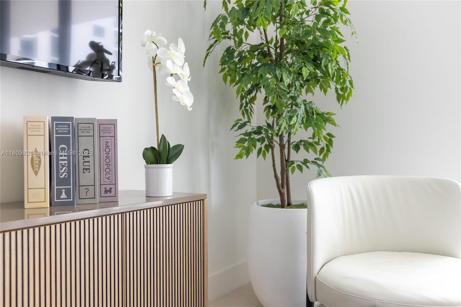 A white chair sits next to a slatted console table with board games and an orchid — 159 NE 6th St # 3001, Miami FL 33132, MIAMI, FL