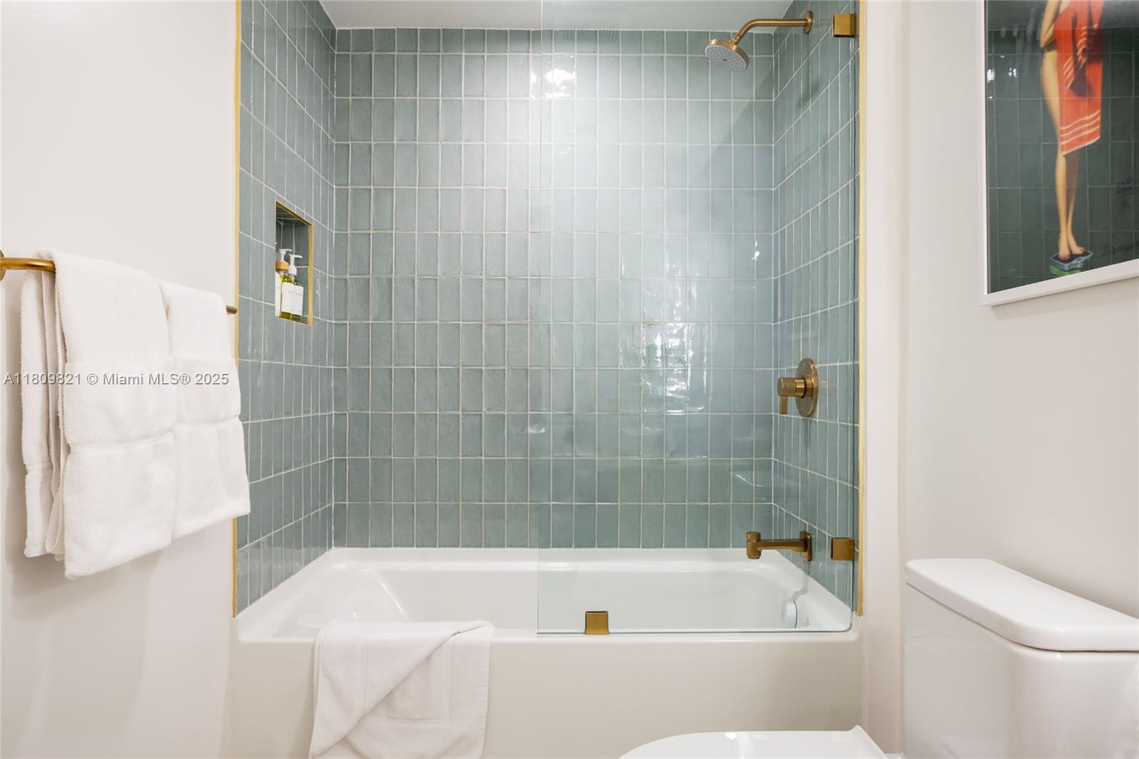 A bathroom features a bathtub with a glass screen, blue tiled walls, and gold fixtures — 159 NE 6th St # 3001, Miami FL 33132, MIAMI, FL