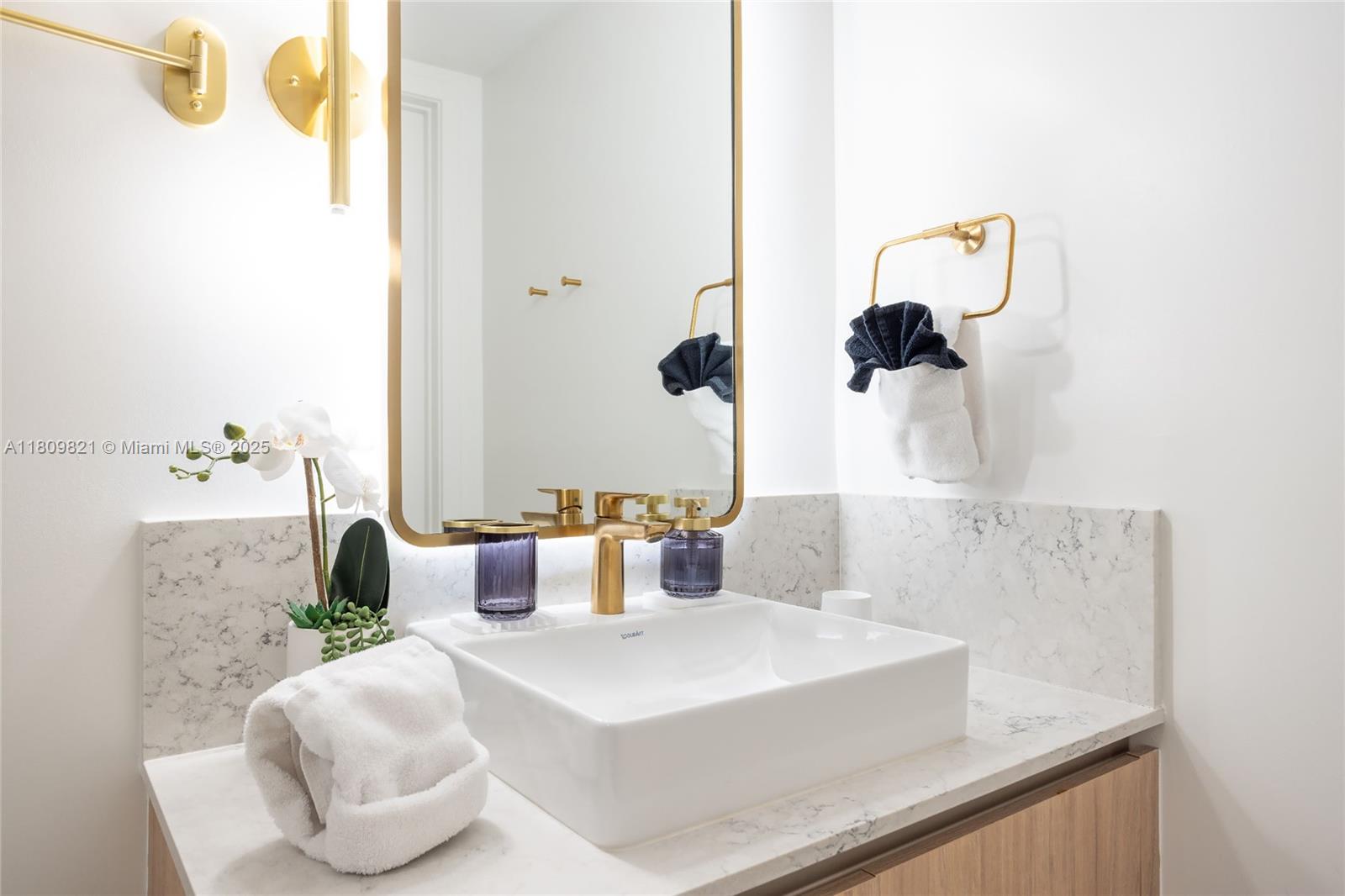A modern bathroom vanity features a white vessel sink, gold fixtures, and a marble countertop — 159 NE 6th St # 3001, Miami FL 33132, MIAMI, FL