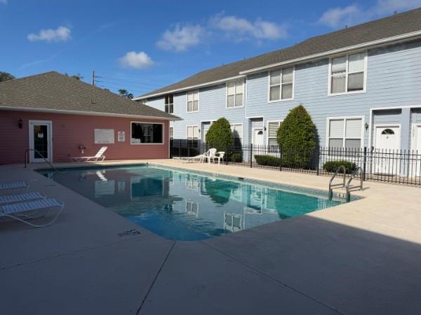 A swimming pool sits in front of a two-story blue apartment building and pink clubhouse — 3940 SW 20TH AVENUE UNIT 1107, GAINESVILLE, FL