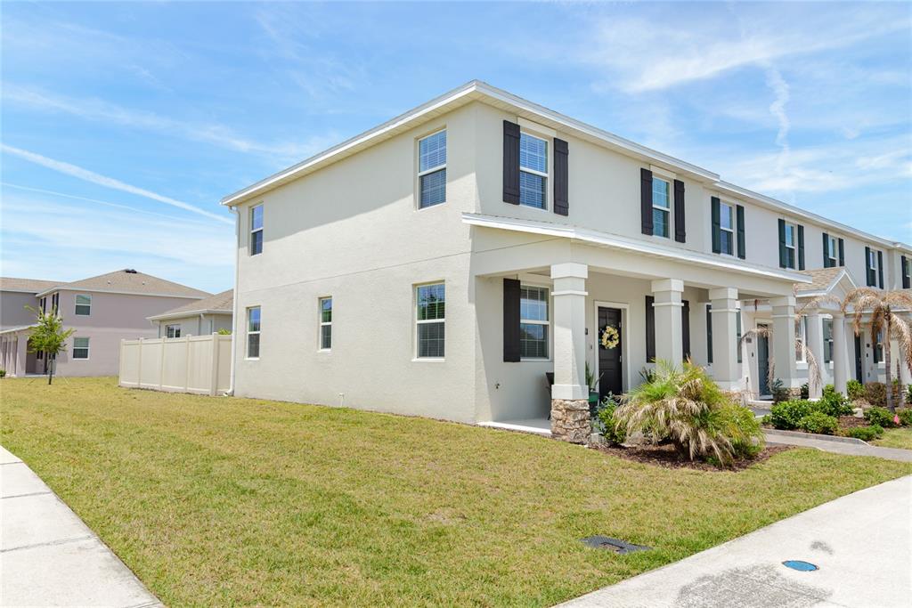 A two-story townhouse with a beige stucco exterior, dark shutters, and a covered front porch — 2579 RELAXING LANE, KISSIMMEE, FL