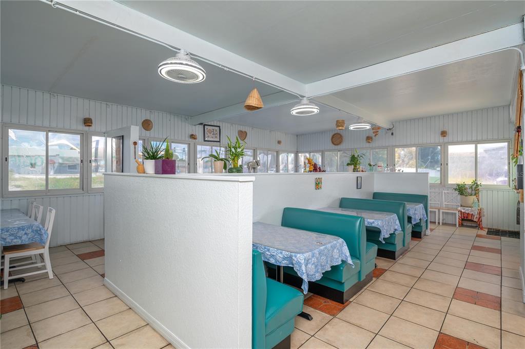 A dining room features teal booths, blue floral tablecloths, and tile flooring under ceiling lights — 114 W CENTRAL AVENUE, LAKE WALES, FL