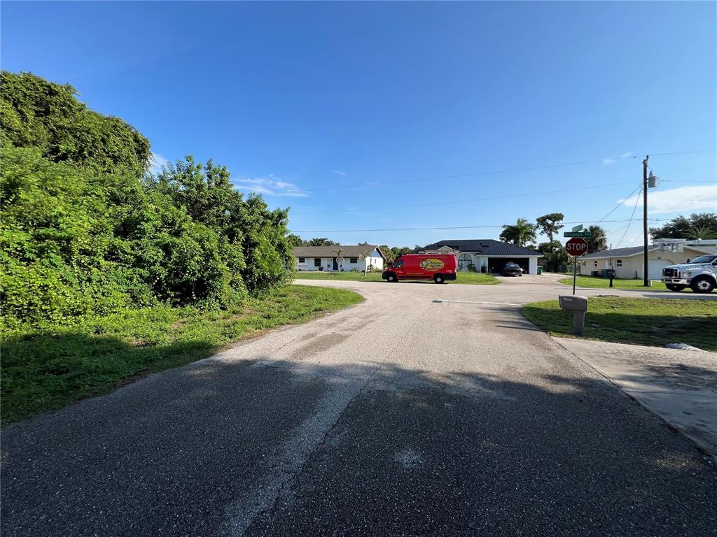 A residential street corner features a stop sign, a red van, and nearby houses — 3239 MANHATTAN STREET, PORT CHARLOTTE, FL