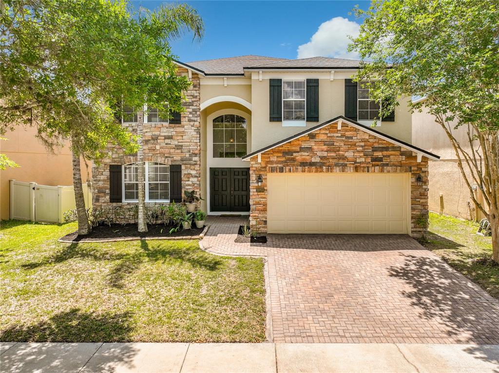 A two-story house with a stone facade, a two-car garage, and black window shutters — 12703 MOSS PARK RIDGE DRIVE, ORLANDO, FL