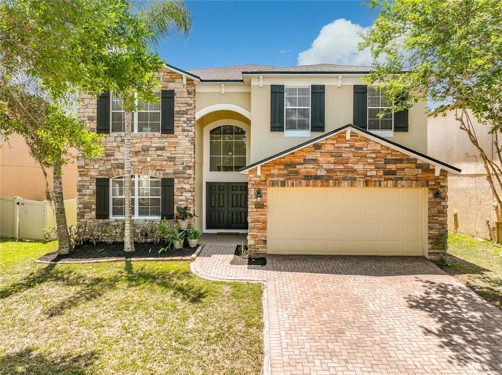 A two-story house with stone veneer siding, a two-car garage, and a paved driveway — 12703 MOSS PARK RIDGE DRIVE, ORLANDO, FL