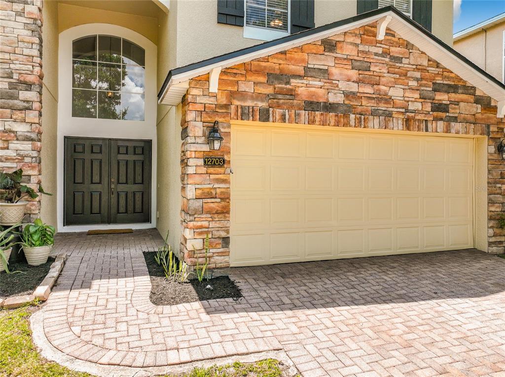 A two-story suburban house features a stone facade, a two-car garage, and a paved driveway — 12703 MOSS PARK RIDGE DRIVE, ORLANDO, FL