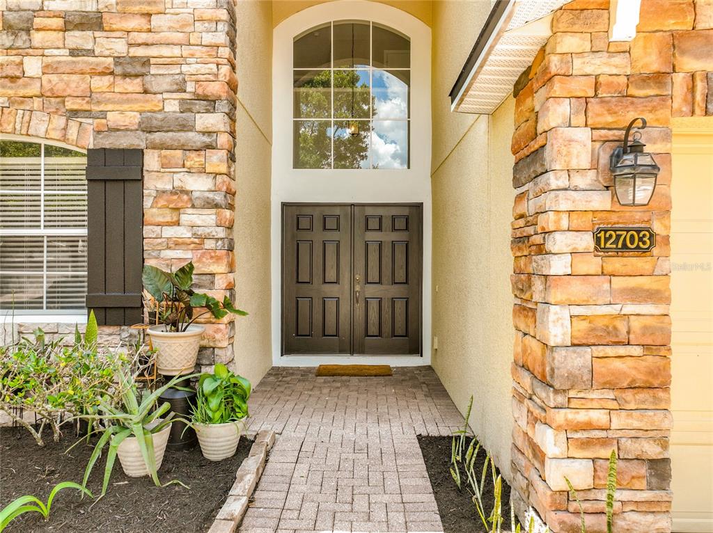 The exterior of a two-story house features stone veneer, a double front door, and a driveway — 12703 MOSS PARK RIDGE DRIVE, ORLANDO, FL