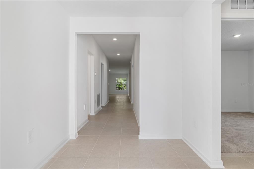 A tiled hallway leads from a white entryway toward a window at the far end — 4814 YELLOW ELDER WAY, KISSIMMEE, FL