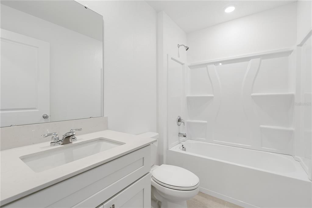 A modern bathroom features a white vanity, a toilet, and a white tub-shower combination — 4814 YELLOW ELDER WAY, KISSIMMEE, FL