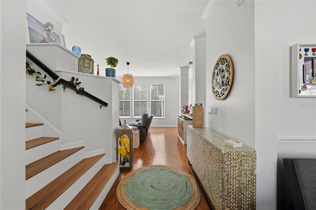 A view of an entryway with wooden stairs, a patterned console table, and hardwood floors — 181 LONGVIEW AVE, KISSIMMEE, FL