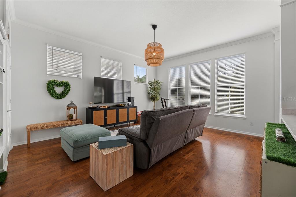 A living room features hardwood floors, a gray sofa, a television console, and large windows — 181 LONGVIEW AVE, KISSIMMEE, FL