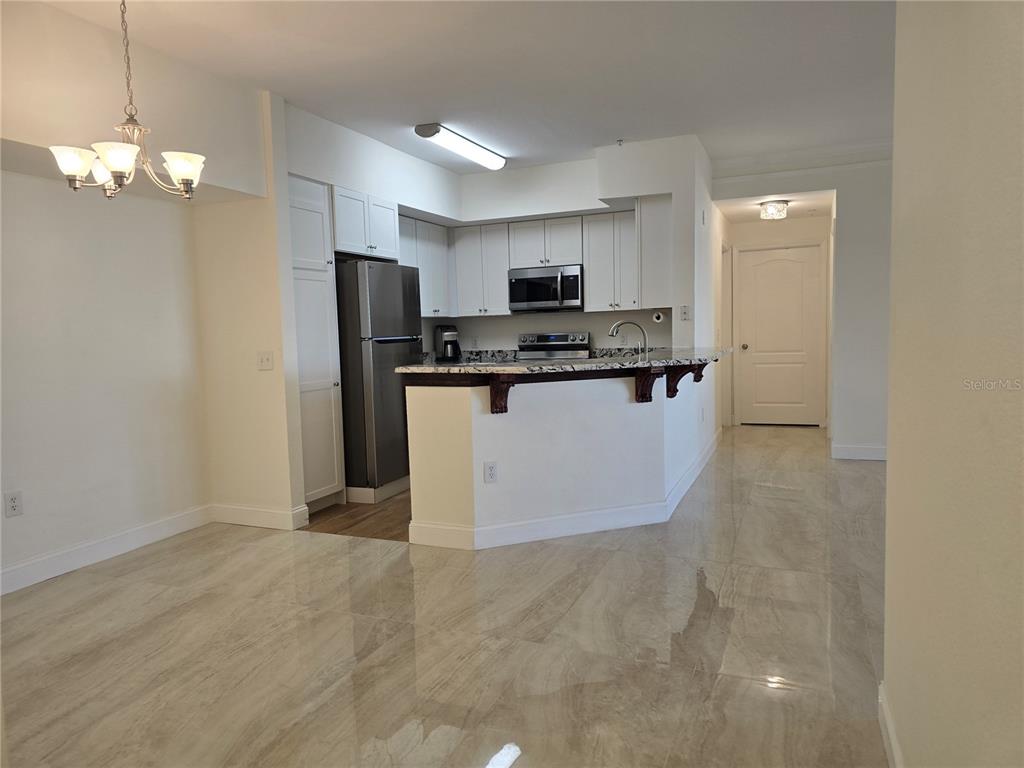 A kitchen with white cabinets, stainless steel appliances, and a granite breakfast bar — 4170 CENTRAL SARASOTA PARKWAY UNIT 412, SARASOTA, FL