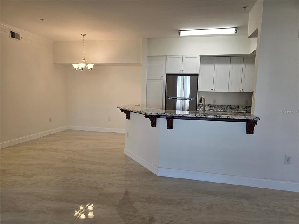 A kitchen with white cabinets and granite countertops overlooks an open dining area — 4170 CENTRAL SARASOTA PARKWAY UNIT 412, SARASOTA, FL