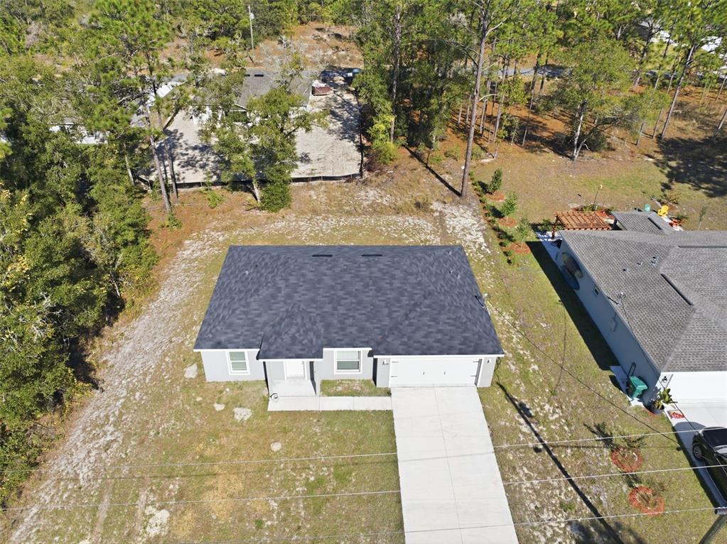 An aerial view shows a single-story house with a dark roof and concrete driveway — 2039 W SHELLBARK DRIVE, CITRUS SPRINGS, FL