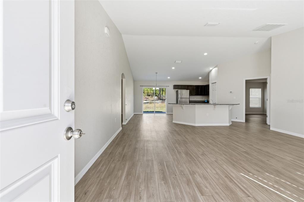 An open-concept living area features light wood-look flooring, a kitchen island, and sliding glass doors — 2039 W SHELLBARK DRIVE, CITRUS SPRINGS, FL