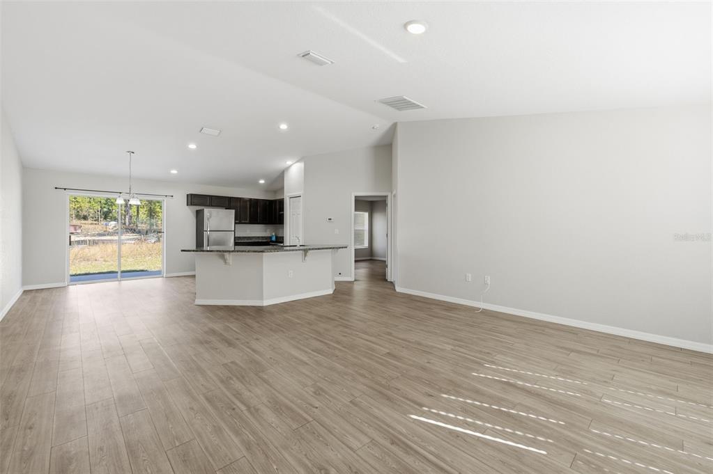 An open-concept living area features light wood-look flooring, a kitchen island, and sliding glass doors — 2039 W SHELLBARK DRIVE, CITRUS SPRINGS, FL