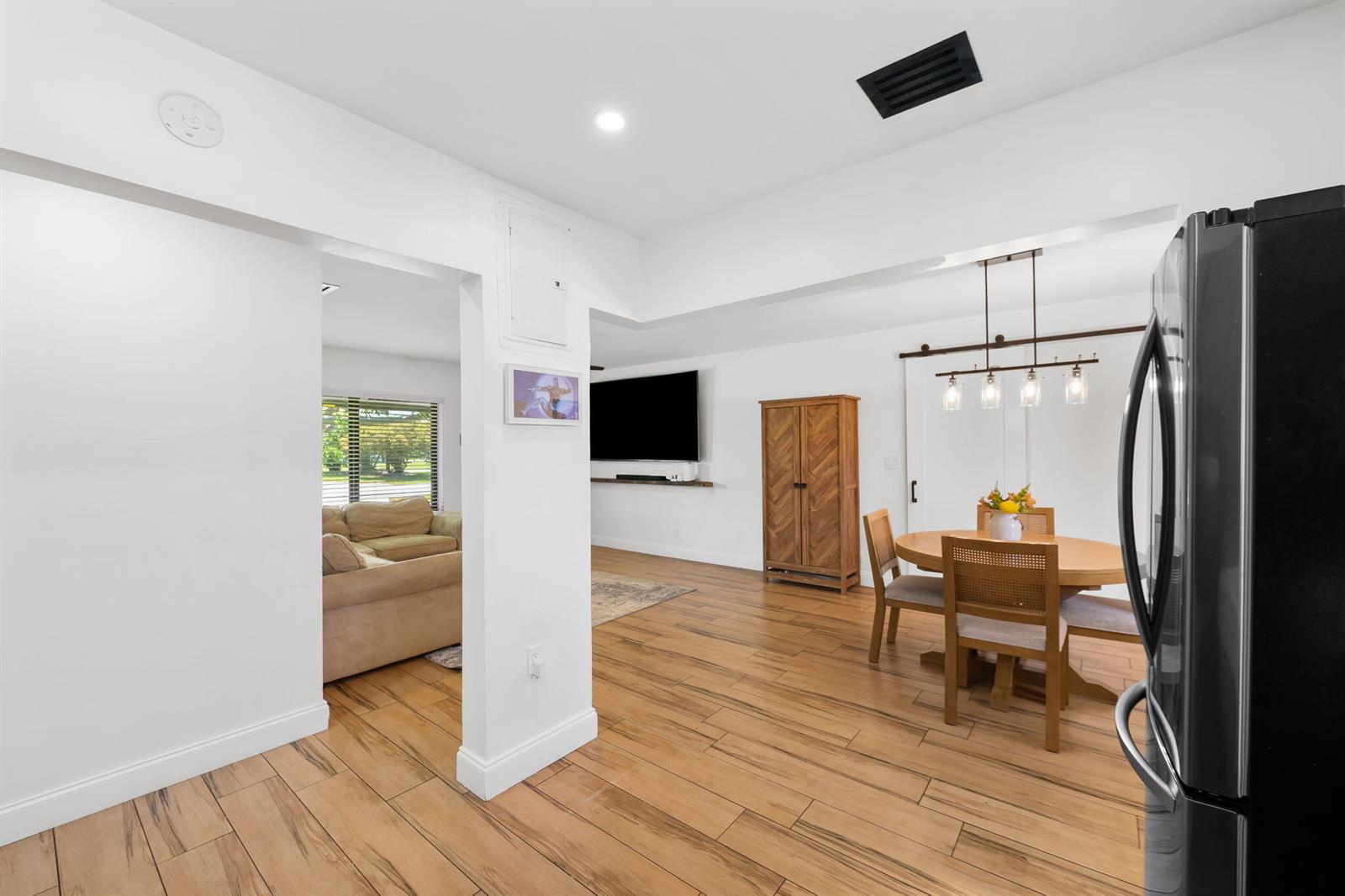 A bright open-concept living and dining area features wood-look tile flooring and white walls — 1032 SW 1st Terrace, Pompano Beach FL 33060, POMPANO BEACH, FL