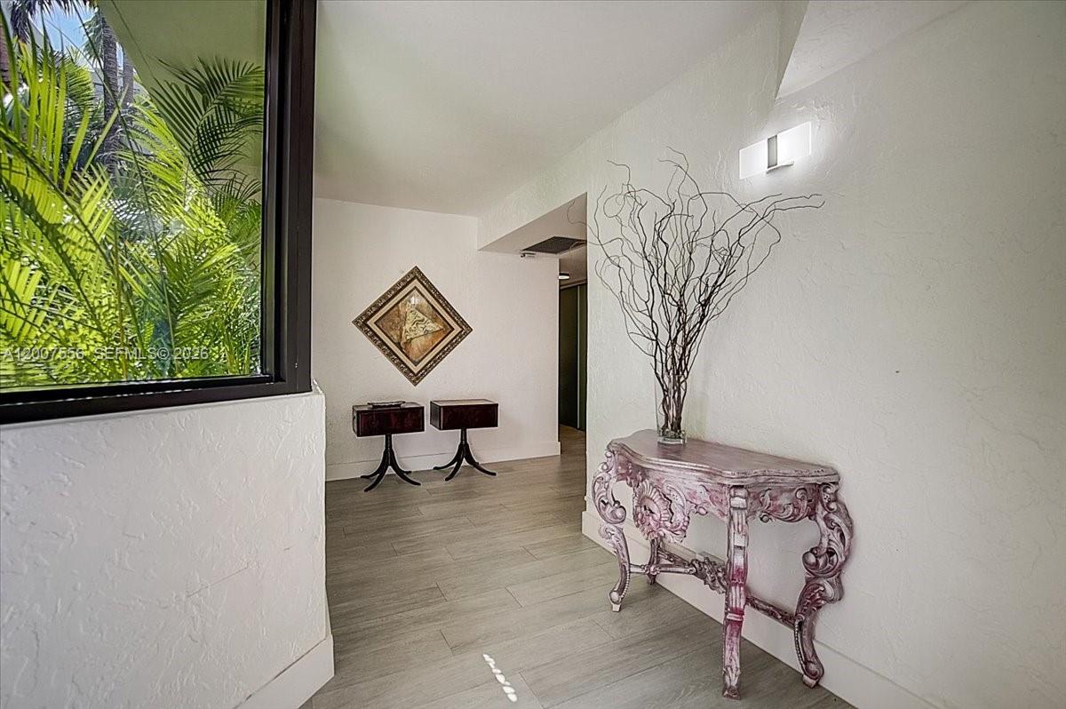 A bright entryway features light wood-look tile flooring, a decorative console table, and wall art — 101 E Crandon Blvd # 276, Key Biscayne FL 33149, KEY BISCAYNE, FL