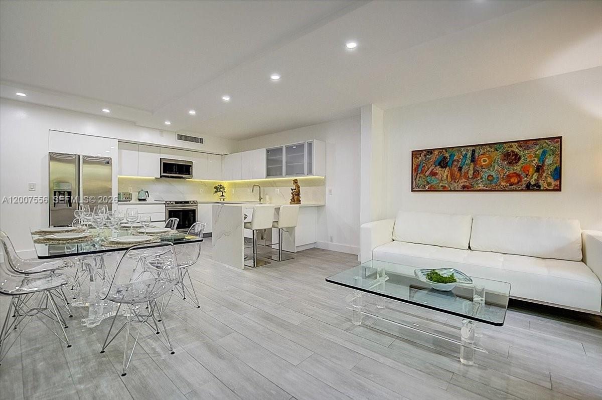This open-concept living area features a modern kitchen, dining table, and white sofa — 101 E Crandon Blvd # 276, Key Biscayne FL 33149, KEY BISCAYNE, FL