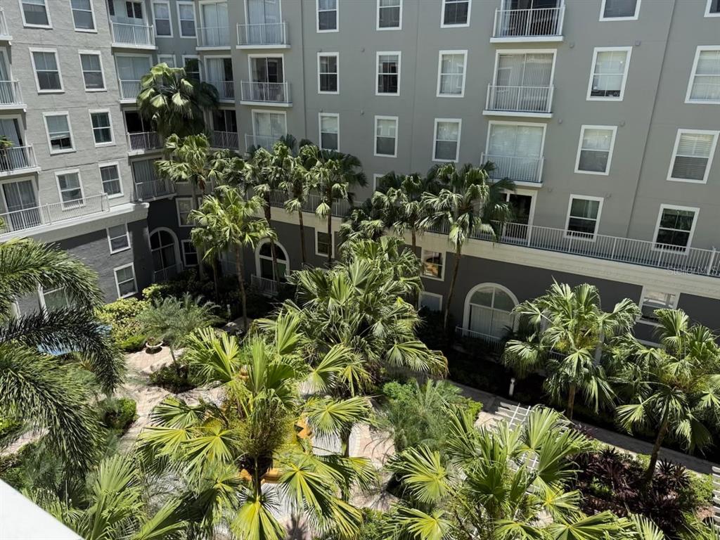 An elevated view of a courtyard with palm trees surrounded by a multi-story apartment building — 700 S HARBOUR ISLAND BOULEVARD UNIT 422, TAMPA, FL